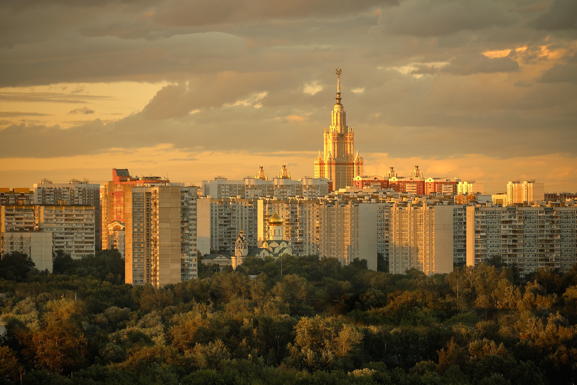 The tower of Moscow State University and Andrey Rublev modern church surrounded by residential houses in Ramenki district, sunset, of Moscow.